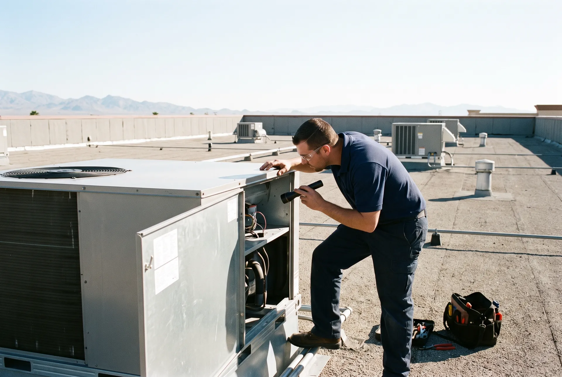 Technician servicing a packaged rooftop unit on a flat commercial roof in Las Vegas